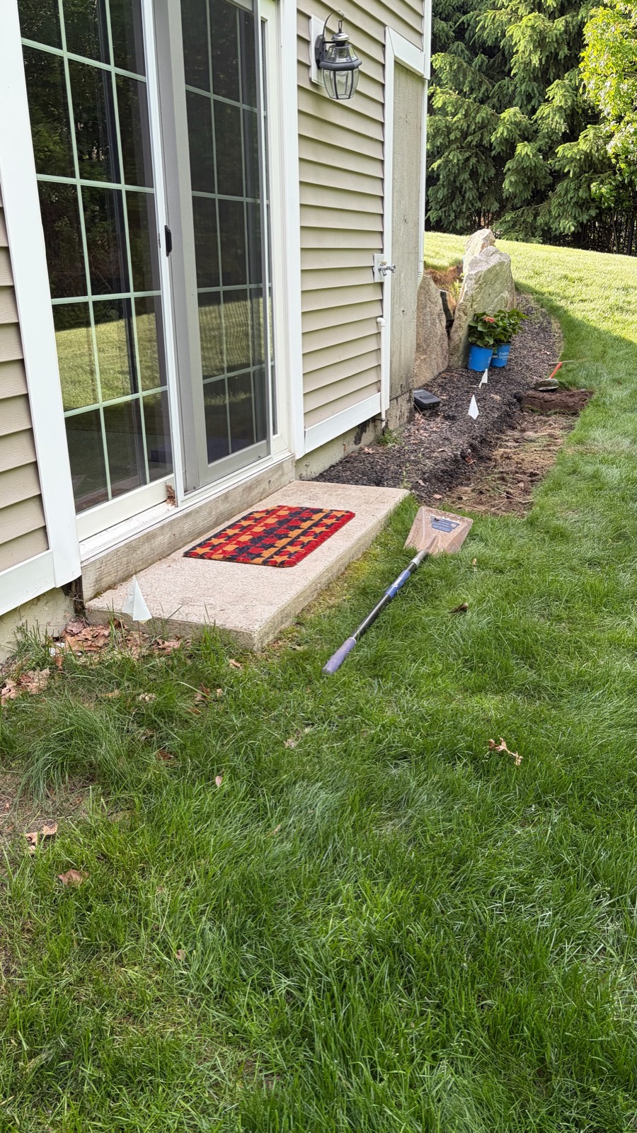 Before: bare dirt bed beside patio door